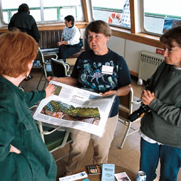 Lyla Snover (white sweatshirt) and Rowena Williamson (with poster) serve as 'ship's naturalists' on the Whidbey Island ferries, talking with visitors about non-point-source pollution and other topics. (c) Laurence Chen