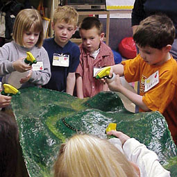 Curlew kindergartners spray spring rain on a model of their watershed.