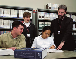 Terri Levien and Danial Baker (standing) work with pharmacy students Tyson Henderson ('02 Ph.D.) and Anh Tran ('02 Ph.D.) to help pharmacists identify drugs and their effects. Terri Levien and Danial Baker (standing) work with pharmacy students Tyson Henderson ('02 Ph.D.) and Anh Tran ('02 Ph.D.) to help pharmacists identify drugs and their effects.