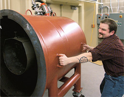 Cory Bakeman pulls the catch chamber off the back of the gun to retrieve the fired projectile.