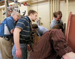James Asay (left) looks on while the project engineer Kent Perkins ('03 Mech. Engr.), project engineer Kurt Zimmerman ('90 Sci., '92 M.S. Phys.), and guest Dave Strange put the finishing touches on the new two-phase gun in the basement of the Institute for Shock Physics.