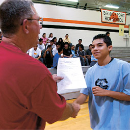 In lieu of a diploma, students practicing commencement get a handshake and a list of graduation requirements from a school board member.