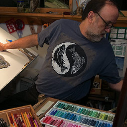 At work in his studio, Troll takes a break from hand coloring to change a CD.