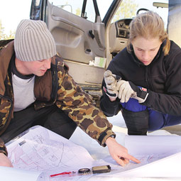 Cooley and wildlife technician Gabe Wilson '04 search maps for roads that will take them close to a cougar's last known location, as reported by a GPS transmitter on the cat's collar.