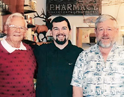Don Cox ’46, Matt Cox ’05 D. Pharm., and David Cox ’71 have operated the South Bend Pharmacy for 55 years. <em>Video frame courtesy South Bend Pharmacy</em>