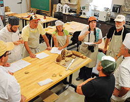 Jeffrey Hamelman of King Arthur Flour (in the white chef’s hat) leads a local grains workshop at the Bread Lab. <em>Photo Kim Binczewski</em>